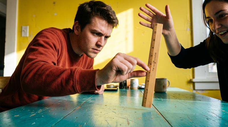 A man catches a falling ruler as his friend watches, illustrating reaction time in a feature on L-theanine and attention.